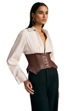 Woman wearing a white blouse with a brown corset over a wooden panel background